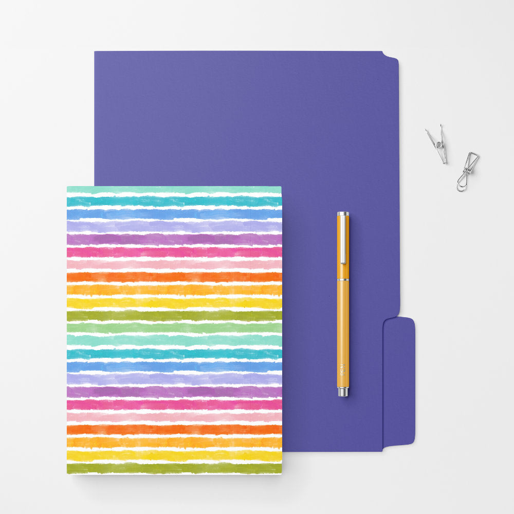 Rainbow striped hardcover notebook on a purple folder with a yellow pen and clips